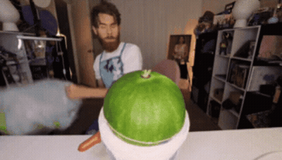 A Man With A Beard Is Cutting A Watermelon Into A Bowl . GIF
