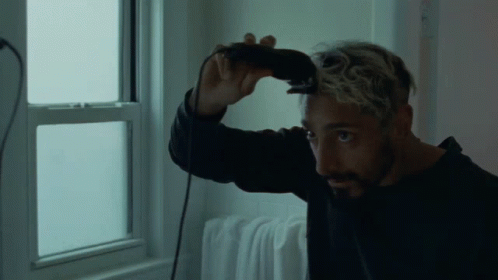 A Man With A Beard Is Cutting His Hair With A Clipper GIF
