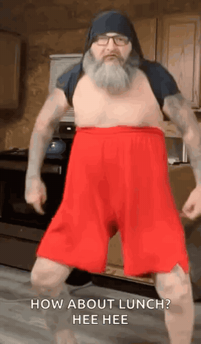 A Man With A Beard Is Dancing In A Kitchen Wearing Red Shorts . GIF