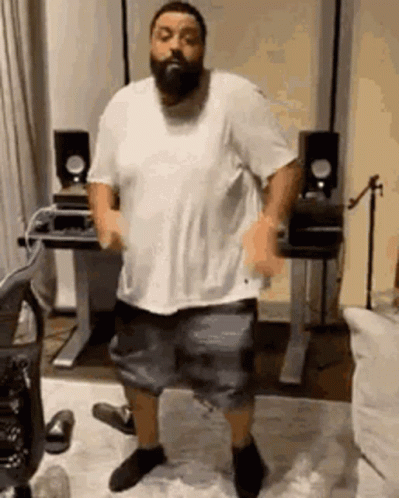 A Man With A Beard Is Dancing In A Room In Front Of A Desk And Speakers . GIF