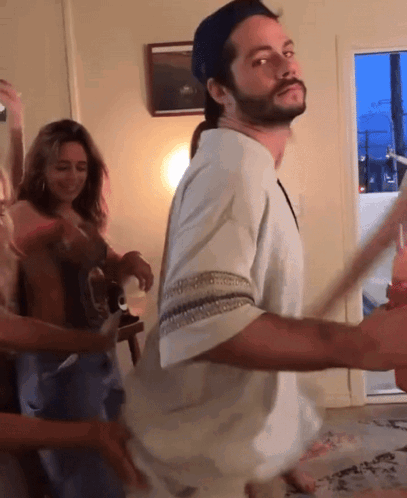 A Man With A Beard Is Dancing In A Room With A Woman Behind Him GIF