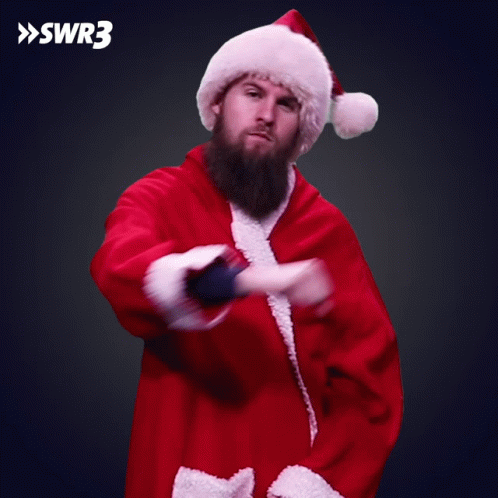 A Man With A Beard Is Dressed In A Santa Suit And Hat GIF