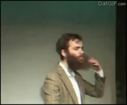 A Man With A Beard Is Drinking A Beer From A Glass . GIF