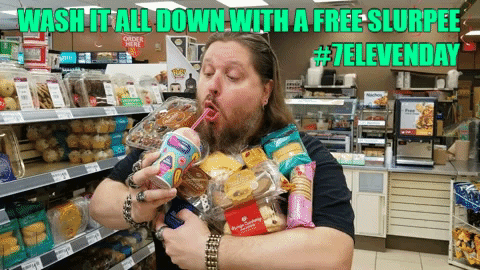 A Man With A Beard Is Drinking A Slurpee From A Straw In A Store GIF