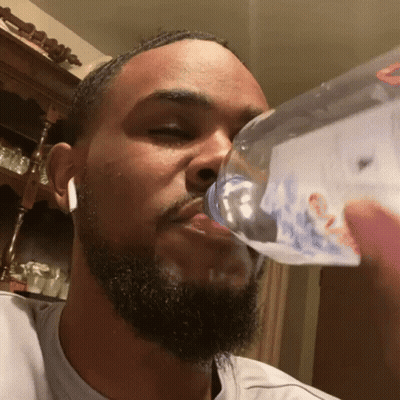 A Man With A Beard Is Drinking From A Bottle That Has The Word Bud Light On It GIF