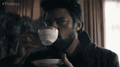 A Man With A Beard Is Drinking From A Cup Of Coffee . GIF