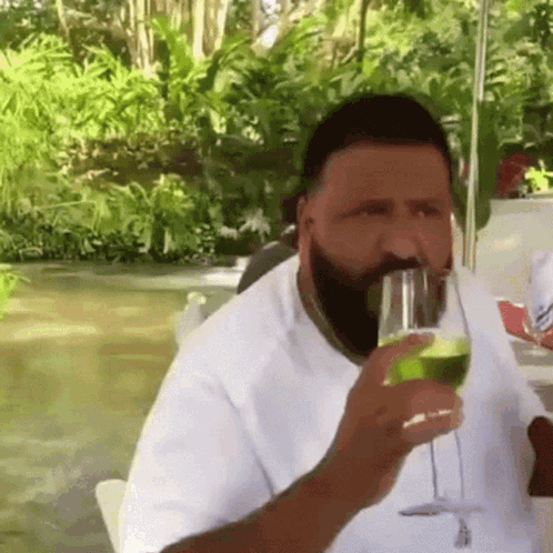 A Man With A Beard Is Drinking From A Glass Of Wine . GIF