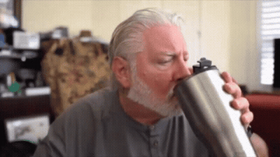 A Man With A Beard Is Drinking From A Stainless Steel Tumbler . GIF