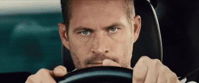 A Man With A Beard Is Driving A Car . GIF