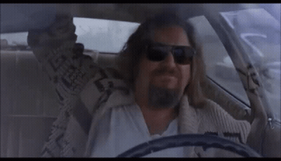 A Man With A Beard Is Driving A Car And Wearing Sunglasses . GIF