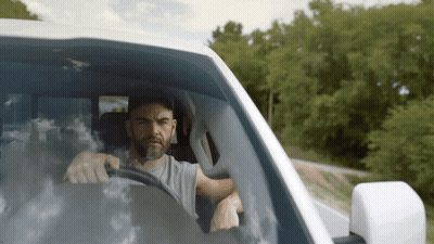 A Man With A Beard Is Driving A Car GIF