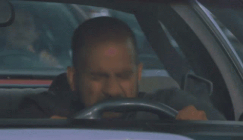 A Man With A Beard Is Driving A Car With His Eyes Closed GIF