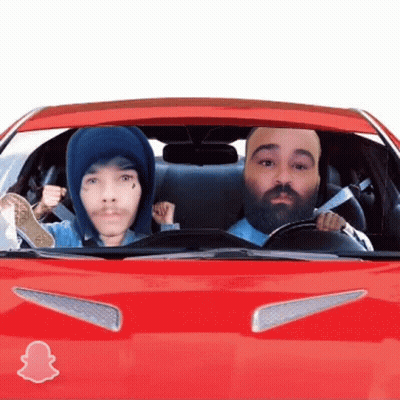 A Man With A Beard Is Driving A Red Car With A Snapchat Logo On The Hood GIF