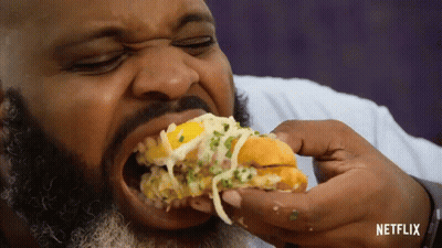 A Man With A Beard Is Eating A Sandwich With Netflix Written In The Corner GIF