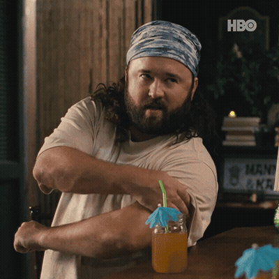 A Man With A Beard Is Flexing His Muscles In Front Of A Hbo Sign GIF