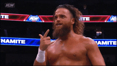 A Man With A Beard Is Giving The Middle Finger In Front Of A Sign That Says Namite GIF