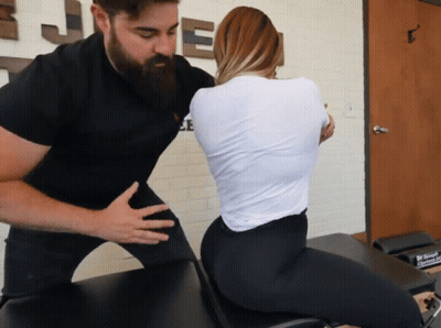 A Man With A Beard Is Helping A Woman With Her Back On A Table GIF