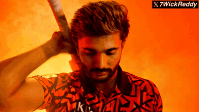 A Man With A Beard Is Holding A Bat In Front Of A Sign That Says 7Wick Reddy GIF