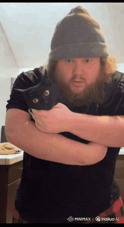 A Man With A Beard Is Holding A Black Cat In His Hands GIF