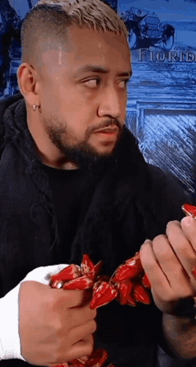 A Man With A Beard Is Holding A Bunch Of Red Peppers With The Word Florh On The Wall Behind Him GIF