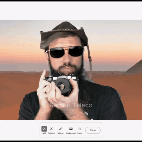 A Man With A Beard Is Holding A Camera With The Name Ramon Teleco In The Corner GIF