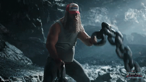 A Man With A Beard Is Holding A Chain With The Word Thor Written On It GIF