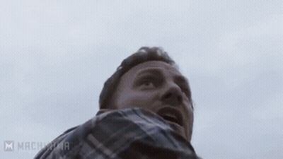 A Man With A Beard Is Holding A Chainsaw In His Hands . GIF