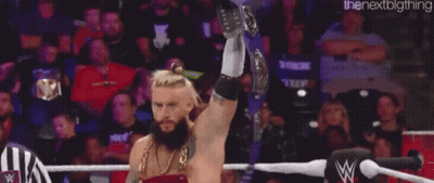 A Man With A Beard Is Holding A Championship Belt In The Air . GIF