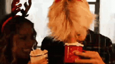 A Man With A Beard Is Holding A Cup Of Hot Chocolate Next To A Woman Wearing Antlers . GIF
