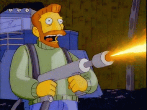A Man With A Beard Is Holding A Flamethrower In His Hands GIF