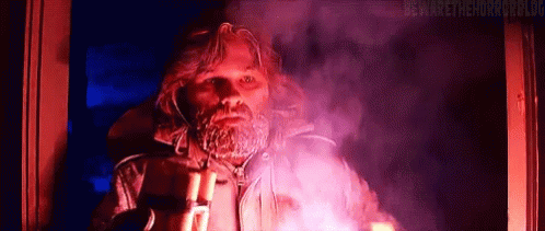 A Man With A Beard Is Holding A Flashlight In His Hand . GIF