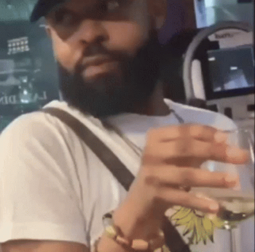 A Man With A Beard Is Holding A Glass Of Wine In His Hand GIF