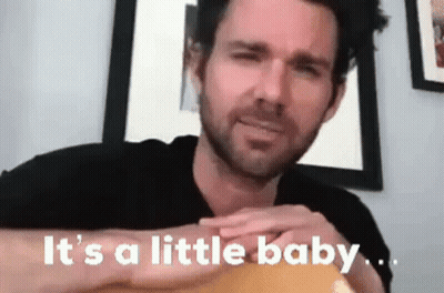 A Man With A Beard Is Holding A Guitar And Says `` It 'S A Little Baby . '' GIF