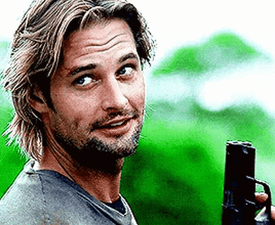 A Man With A Beard Is Holding A Gun And Smiling . GIF