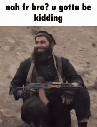 A Man With A Beard Is Holding A Gun And Smiling While Sitting In The Dirt . GIF