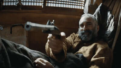A Man With A Beard Is Holding A Gun GIF