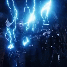 A Man With A Beard Is Holding A Hammer And Being Struck By Lightning In A Dark Room . GIF