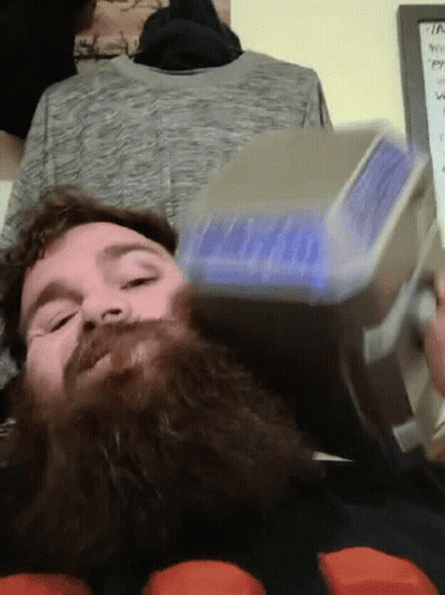 A Man With A Beard Is Holding A Hammer In His Hand GIF