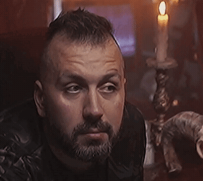 A Man With A Beard Is Holding A Knife In His Hand GIF