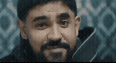 A Man With A Beard Is Holding A Knife In His Hand And Making A Face . GIF