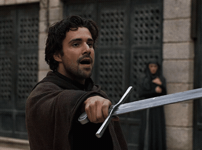 A Man With A Beard Is Holding A Large Sword GIF