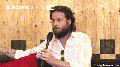 A Man With A Beard Is Holding A Microphone In Front Of A Sign That Says Fuji Rock Festival 17 GIF