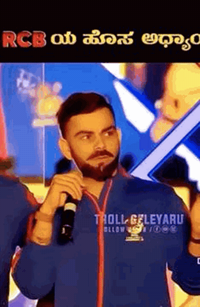 A Man With A Beard Is Holding A Microphone In His Hand And Talking Into It . GIF