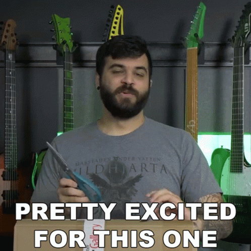 A Man With A Beard Is Holding A Pair Of Scissors In Front Of A Wall Of Guitars And Says Pretty Excited GIF