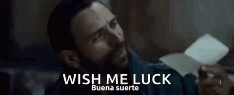 A Man With A Beard Is Holding A Piece Of Paper With The Words `` Wish Me Luck '' Written On It . GIF