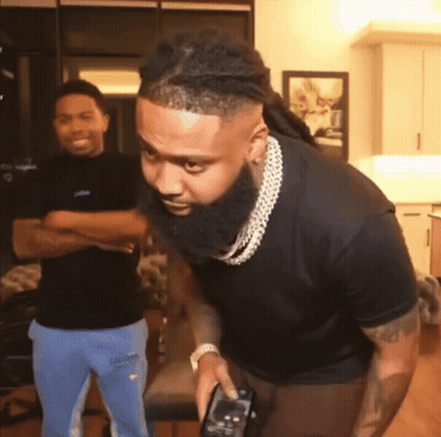 A Man With A Beard Is Holding A Remote Control In His Hand GIF