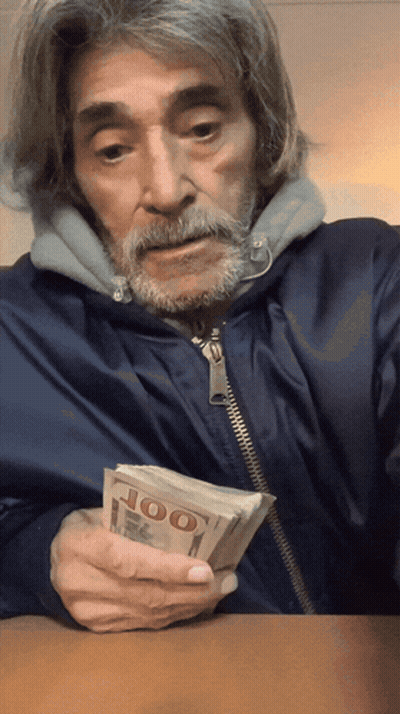 A Man With A Beard Is Holding A Stack Of 100 Dollar Bills GIF