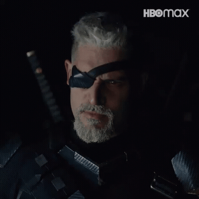 A Man With A Beard Is Holding A Sword And Wearing A Black Eye Patch With The Word Deathstroke On It GIF
