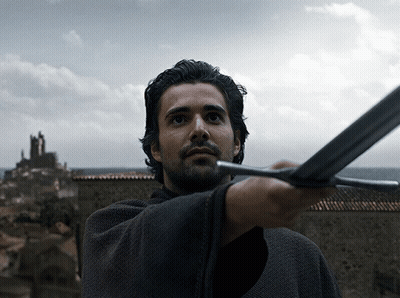 A Man With A Beard Is Holding A Sword In His Right Hand GIF