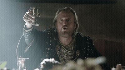 A Man With A Beard Is Holding A Wine Glass In His Hand GIF